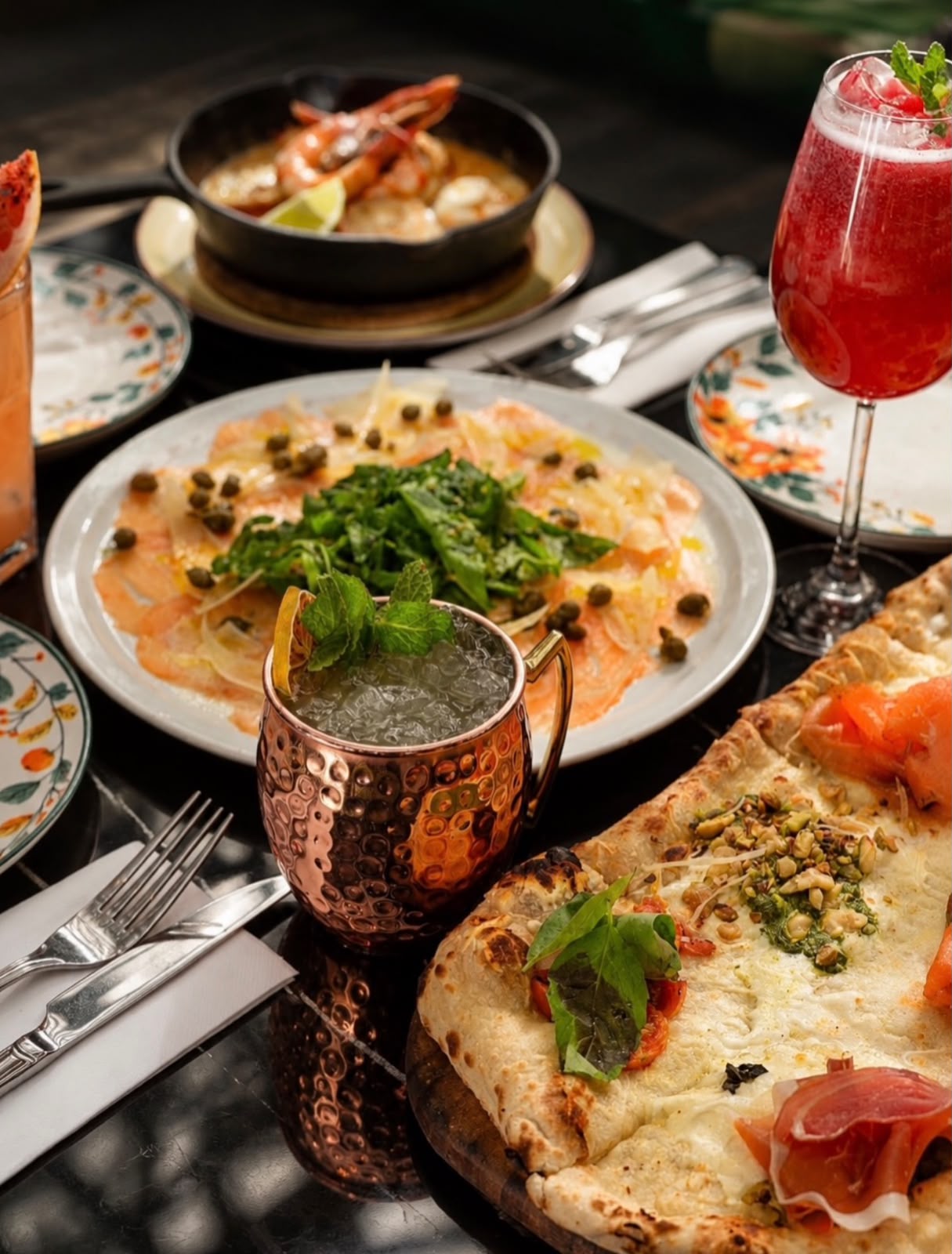 Mesa servida con mariscos, carpaccio y cócteles